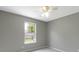 This bedroom has a window overlooking the backyard, neutral gray walls, gray carpet, and a fan at 14255 Holly Berry Cir, Fishers, IN 46038