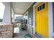 Close-up of the cozy front porch featuring stylish seating, pineapple decor and a bright yellow door at 14982 Dawnhaven Dr, Westfield, IN 46074