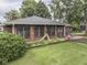 Backyard view of a brick home with enclosed patio, landscaped yard, and lush greenery at 1504 Mcclure Rd, Columbus, IN 47201