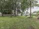 Large backyard showcasing mature trees, a brick fire pit with chairs, and fencing at 1504 Mcclure Rd, Columbus, IN 47201