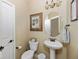 Charming powder room features a pedestal sink, decorative mirror, and updated fixtures at 15879 Viking Commander Way, Westfield, IN 46074