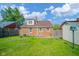 Back exterior view showing a brick home with green lawn and partial fence at 2908 Sherman St, Anderson, IN 46016