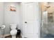A clean bathroom with a toilet, a framed picture, and a glass enclosed shower at 2928 Mounds Rd, Anderson, IN 46016