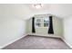 Small bedroom with neutral carpet and a large window covered with black curtains at 2928 Mounds Rd, Anderson, IN 46016