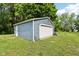 Detached garage with blue siding and a white garage door, providing ample storage and parking space, sitting on a green lawn at 2928 Mounds Rd, Anderson, IN 46016