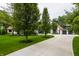 A long concrete driveway leads to a charming home surrounded by lush greenery and mature trees at 3549 W 131St St, Carmel, IN 46032
