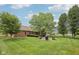 Large backyard featuring a fire pit with chairs, mature trees, manicured lawn, and privacy fencing at 3571 S Cedar Creek Ln, New Palestine, IN 46163