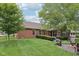 Spacious backyard features lush grass, mature trees, fire pit, and brick home with manicured landscaping at 3571 S Cedar Creek Ln, New Palestine, IN 46163