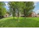 Lush backyard with mature trees, manicured lawn, firepit, and access to the home's exterior at 3571 S Cedar Creek Ln, New Palestine, IN 46163