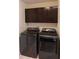 The laundry room features black front load washer and dryer, tile floor and overhead cabinets at 4353 W Parkway Ct, New Palestine, IN 46163