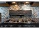 Close-up of a black stovetop and the colorful mosaic tile backsplash in the kitchen at 4353 W Parkway Ct, New Palestine, IN 46163