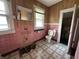 Bathroom with pink tile walls, checkered flooring, and a window with natural light at 4709 E New York St, Indianapolis, IN 46201
