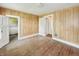 Bedroom with hardwood floors, wood-paneled walls, and multiple entryways at 4709 E New York St, Indianapolis, IN 46201