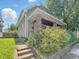 Side view of a cozy home, showcasing its siding, porch with brick columns, and vibrant green foliage at 4709 E New York St, Indianapolis, IN 46201
