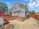Backyard area with a grey house, small deck, red fence, and a hot tub at 4715 E New York St, Indianapolis, IN 46201
