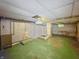 Unfinished basement space with green floor, exposed pipes, shower, and basic lighting fixtures at 4715 E New York St, Indianapolis, IN 46201
