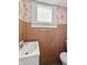 This bathroom includes a sink, a towel bar, a toilet, wood paneled walls, and patterned wallpaper at 4715 E New York St, Indianapolis, IN 46201