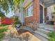 Side view of a brick home with a gray exterior, showcasing a red fence and some plants near the steps at 4715 E New York St, Indianapolis, IN 46201