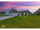 Charming single-story home with a brick facade and a well-manicured lawn at twilight at 59 Manchester Dr, Trafalgar, IN 46181