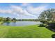Expansive backyard featuring a serene lake view, lush lawn, and mature trees on a sunny day at 5940 Chapmans Trl, Carmel, IN 46033