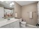 Neutral bathroom with white vanity, toilet, mirror, and floral shower curtain at 5940 Chapmans Trl, Carmel, IN 46033