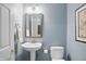Stylish powder room with a pedestal sink, framed mirror, and blue walls at 5940 Chapmans Trl, Carmel, IN 46033