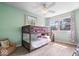 Bright bedroom features a bunk bed, multiple windows, hardwood floors, ceiling fan, and mint green walls at 6133 Buttonwood Dr, Noblesville, IN 46062
