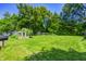 Large, well-manicured backyard with mature trees, a vegetable garden, and a play area at 6514 Jackson St, Indianapolis, IN 46241