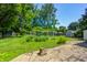 Expansive backyard with lush greenery, a stone walkway, raised garden beds, and mature trees at 6514 Jackson St, Indianapolis, IN 46241