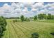 Expansive backyard with a play set, mature trees, and green field views, perfect for outdoor activities at 6702 W Willow Grove Dr, New Palestine, IN 46163