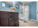 Updated bathroom featuring modern vanity, toilet, and shower with glass door, complemented by stylish blue walls at 6702 W Willow Grove Dr, New Palestine, IN 46163