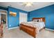 Carpeted bedroom with blue walls featuring a wood bed frame, closet, and white door at 6702 W Willow Grove Dr, New Palestine, IN 46163