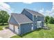 View of a two-story home featuring blue siding, an attached two-car garage, and an outdoor patio area at 6702 W Willow Grove Dr, New Palestine, IN 46163