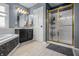 Light and bright bathroom featuring a walk-in shower, tub, vanity with black cabinets and tile flooring at 6702 W Willow Grove Dr, New Palestine, IN 46163