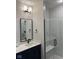 Modern bathroom with a glass enclosed shower, dark blue vanity, and light colored floor tiles at 711 E 16Th St, Indianapolis, IN 46202