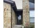Close up of front door featuring stone facade, flower bed, and front storm door at 7950 Eagle Valley Pass, Indianapolis, IN 46214