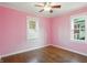 Bright bedroom with hardwood floors, pink walls, white trim, and large windows at 808 N Layman Ave, Indianapolis, IN 46219