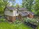 Aerial view of a Tudor-style home showcasing a lush backyard, patio, and mature trees at 8310 Fall Creek Rd, Indianapolis, IN 46256