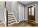 Inviting entryway features a wood-grain door, staircase, coat closet, and beautiful hardwood floors at 8310 Fall Creek Rd, Indianapolis, IN 46256