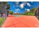 Outdoor tennis court with a red surface and green playing area under a sunny sky and mature trees at 8720 Yardley Ct # 207, Indianapolis, IN 46268