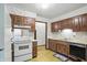 Kitchen with white appliances, wood cabinets, and floral wallpaper, needing updates at 9101 Ditch Rd, Indianapolis, IN 46260
