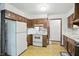 Kitchen featuring white appliances, wood cabinets, and floral wallpaper, ready for renovation at 9101 Ditch Rd, Indianapolis, IN 46260