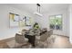 Bright dining room with glass table, seating for eight, modern lighting, and a large window at 9205 Selkirk Ct, Indianapolis, IN 46260