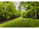 Backyard view showing a fire pit with a grassy lawn and surrounding trees at 10380 Sand Creek Blvd, Fishers, IN 46037