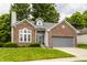 Charming brick home with manicured lawn, gray roof, an attached garage and lush green landscaping at 10380 Sand Creek Blvd, Fishers, IN 46037