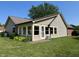 Back exterior view of the home with a sunroom, patio, and greenery at 10976 Mt Vernon N Trl, Indianapolis, IN 46229
