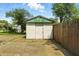 Small, white storage shed with a green corrugated metal roof and adjacent wooden privacy fence at 1120 W 5Th St, Greenfield, IN 46140