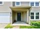 Inviting covered front porch with neutral siding, stylish lighting fixtures, and green door at 1252 Jasmine Dr, Greenfield, IN 46140