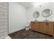 Modern bathroom featuring dual sinks, round mirrors, wood cabinetry, and dark tile flooring at 1409 N Grant Ave, Indianapolis, IN 46201