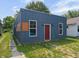 Charming home featuring vertical siding, a red front door, and complemented by landscaped surroundings at 1409 N Grant Ave, Indianapolis, IN 46201